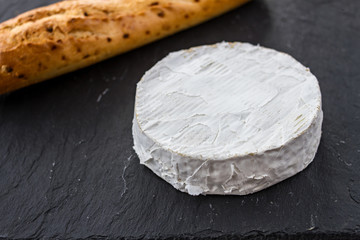 Golden fresh crispy fried baguette and head of Swiss Camembert cheese on a black textured...