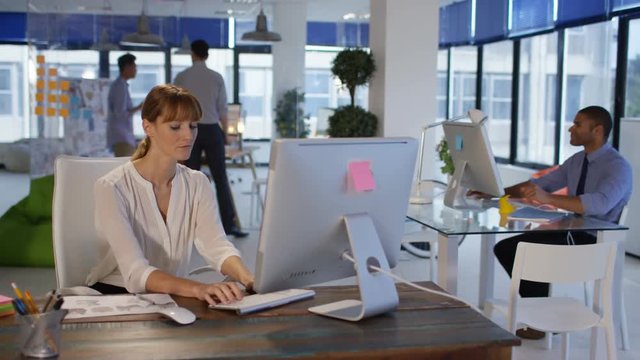 Business group in modern office, focus on woman working on computer.