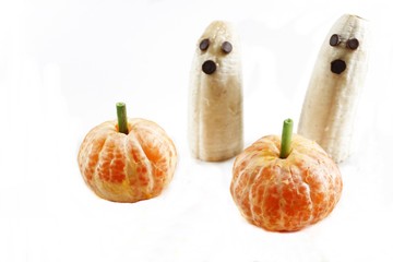 Halloween food Banana ghost and clementine pumpkin isolated on white