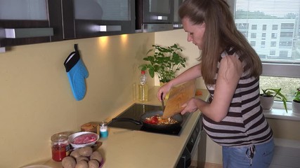 Future mother with big stomach cut tomato and put into baking pan - Powered by Adobe