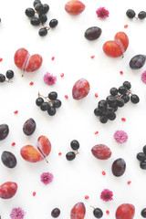 Vertical  composition of fruits on a white background. Pattern made from fresh fruits. Top view, flat design. Collage of plum, grapes, flowers.	