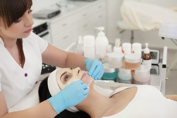 Cosmetologist applying facial cream to the client in the cosmetology office