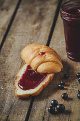 croissant with black currant jam and fresh berries on a wooden table