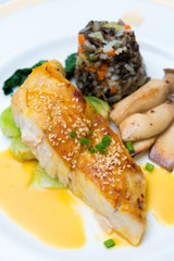 Seared sea bass with orange miso sauce, Wild rice and seasonal vegetable, close up