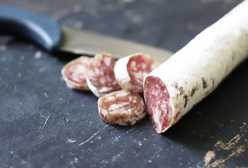 Dry cured sausage with spices on dark background
