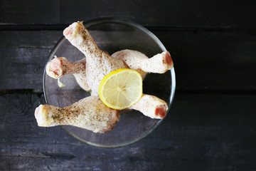 Raw chicken legs with herbs and lemon slice prepared for cooking.