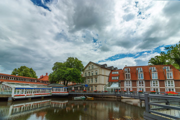 View of the small German town of Luneburg. Beautiful cityscape with reflections of houses on water and sky with clouds.