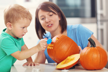 Fototapeta premium Mother and son preparing jack-o-lantern for Halloween