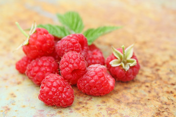 Ripe raspberry with a leaf on an old metal background