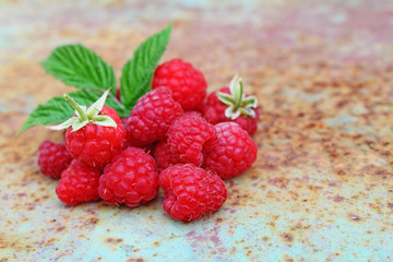 Ripe raspberry with a leaf on an old metal background