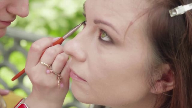 Make up artist applies shades on girl's eyelid before photoshoot