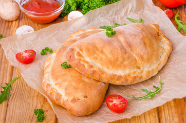 Pizza Calzone with tomato sauce, cheese, herbs, mushrooms and sausages