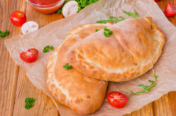 Pizza Calzone with tomato sauce, cheese, herbs, mushrooms and sausages