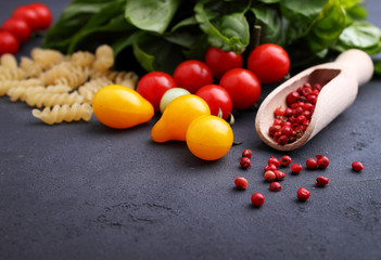 italian food: pasta, basil, tomato, olive oil on a black background, copy space.