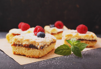 Homemade pie with berries cut into pieces on the black background