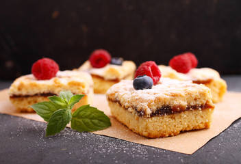 Homemade pie with berries cut into pieces on the black background