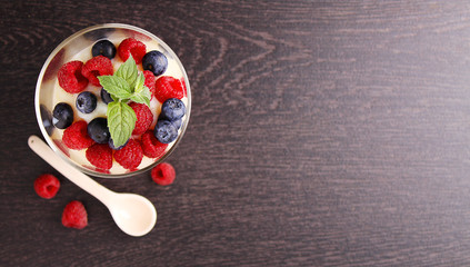 Fototapeta na wymiar Milk pudding with berries in a glass on a black background