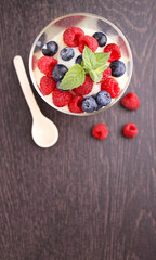 Milk pudding with berries in a glass on a black background