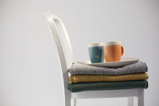 Two ceramic mugs and a plate on a stack of cotton blanquets