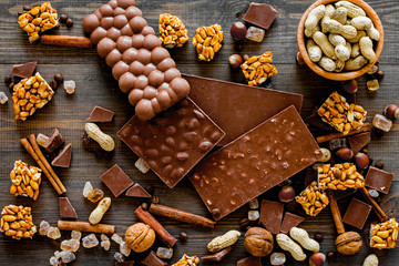 Chocolate with nuts on dark wooden background top view