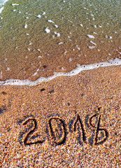 2018 written on the sea sand with gentle wave. Summer day. Natural vertical background with place for text