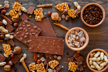 Chocolate with nuts on dark wooden background top view