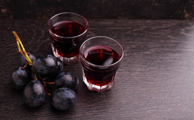 ripe grapes, red wine and a glass on a black background