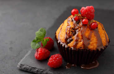 homemade cupcake with chocolate is decorated with mint and berries on a black background