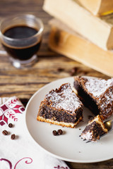 Fototapeta na wymiar sweets and desserts, pastries, delicious chocolate cake with poppy seeds, raisins and powdered sugar with a cup of black coffee on a dark wooden background
