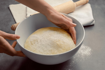 Female chef with dough in bowl on kitchen table