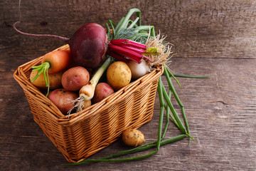 Vegetables in a basket: beets, onions, garlic, dill, potatoes, carrots on an old wooden background