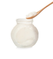 Spoon and jar with coconut oil on white background