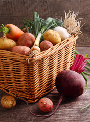 Vegetables in a basket: beets, onions, garlic, dill, potatoes, carrots on an old wooden background