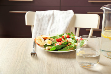 Plate of tasty salad with spinach leaves  on wooden table
