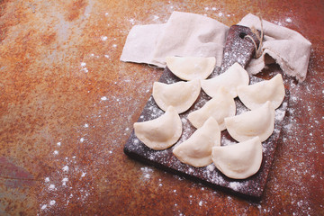 dumplings (varenili) with potato sprinkled with flour on a wooden old board