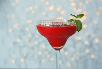 Glass of delicious strawberry daiquiri against blurred lights