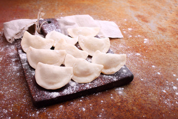 dumplings (varenili) with potato sprinkled with flour on a wooden old board