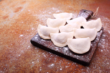 dumplings (varenili) with potato sprinkled with flour on a wooden old board