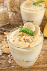 Glass with delicious banana pudding on table