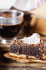 sweets and desserts, pastries, delicious chocolate cake with poppy seeds, raisins and powdered sugar with a cup of black coffee on a dark wooden background