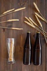 Preparing beer. Barley near beer bottle and glass on wooden background top view