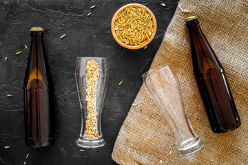 Preparing beer. Barley near beer bottle and glass on black background top view