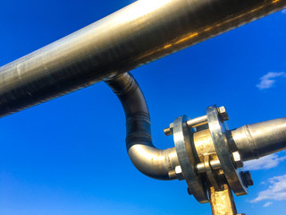 Tubazioni industriiali in inox con valvole e flange su fondale cielo blu 