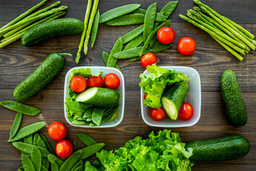 Healthy meal with vegetables tomato, cucumber, asparagus in cotainers on wooden background top view