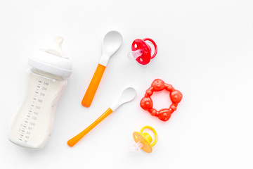 preparation of mixture baby feeding with infant formula powdered milk in bottle with spoons on white background top view