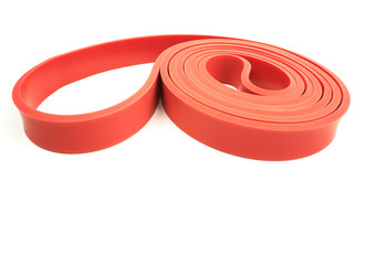 Red exercise resistance band on a white background with writing / copy space