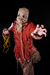 Cosplay, a frightening hero in a sackcloth suit with syringes on his hands on a black background