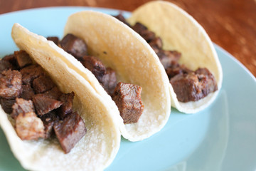 Tacos with steak on a blue plate on a wood background 