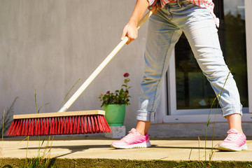 Woman using broom to clean up backyard patio