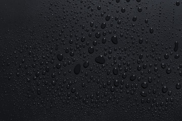 Closeup of black raindrops on a dark surface
